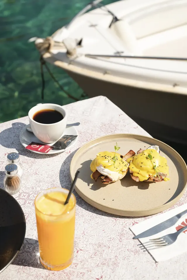 Eggs Benedict and coffee at a waterside table