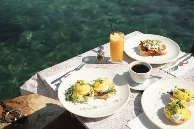 Brunch dishes, coffee and juice on a table by the sea